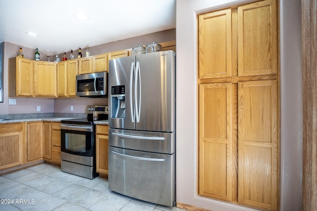 kitchen featuring light brown cabinetry, stainless steel appliances, and light tile patterned floors