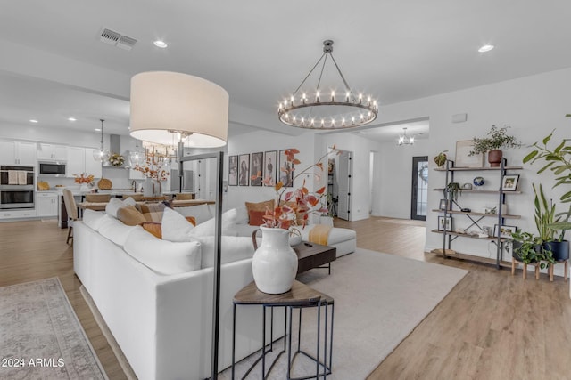 living area featuring recessed lighting, visible vents, an inviting chandelier, and light wood finished floors