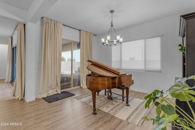 living area with light wood-style flooring, baseboards, and an inviting chandelier