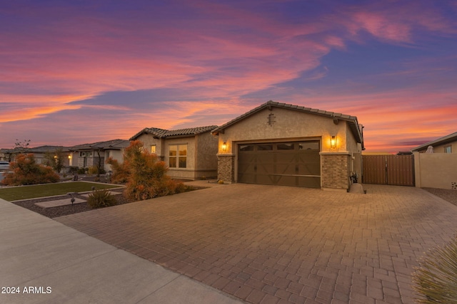 view of front of property featuring stucco siding, decorative driveway, a garage, and a gate