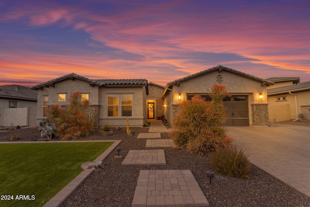 view of front of property featuring stucco siding, a tiled roof, decorative driveway, and a garage