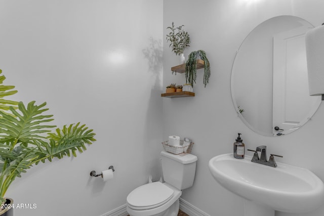 half bath with a sink, baseboards, and toilet