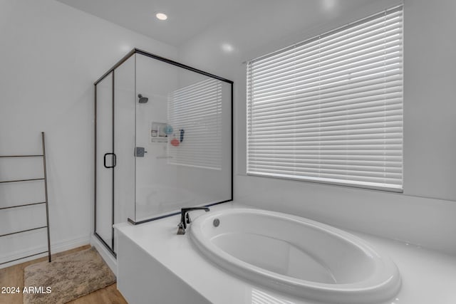 bathroom featuring a garden tub, a healthy amount of sunlight, wood finished floors, and a shower stall