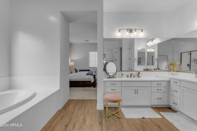 ensuite bathroom featuring connected bathroom, a garden tub, wood finished floors, and vanity