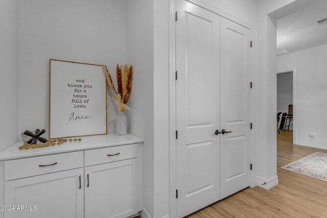 corridor with visible vents, light wood-type flooring, and baseboards