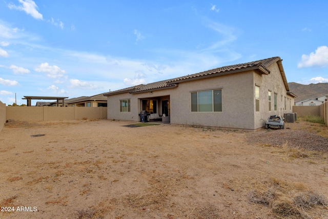 rear view of property with a tiled roof, central air condition unit, a fenced backyard, and stucco siding