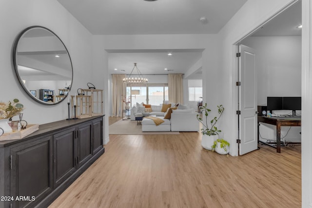 hall with light wood-style floors and an inviting chandelier