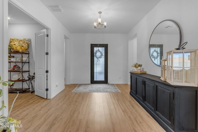 foyer entrance with light wood finished floors, visible vents, a notable chandelier, and baseboards