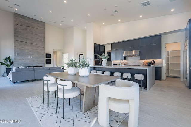 kitchen featuring backsplash, sink, a breakfast bar, and a high ceiling