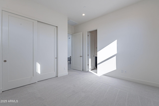 unfurnished bedroom with light colored carpet and a closet