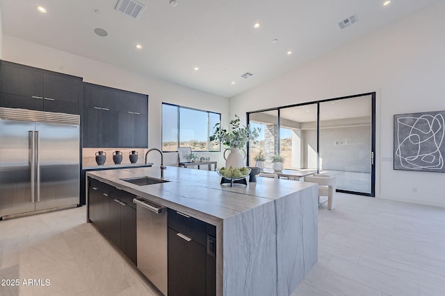 kitchen featuring lofted ceiling, sink, light tile patterned floors, a kitchen island with sink, and stainless steel appliances