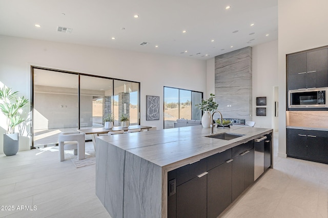 kitchen with built in microwave, sink, lofted ceiling, and a large island with sink