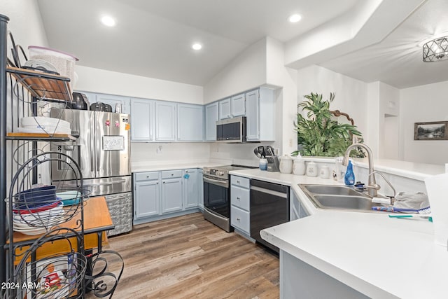 kitchen with wood-type flooring, gray cabinetry, sink, lofted ceiling, and stainless steel appliances