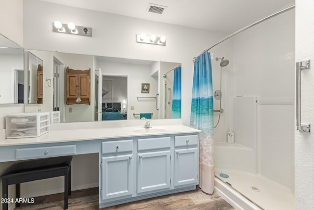 bathroom with hardwood / wood-style flooring, walk in shower, and vanity