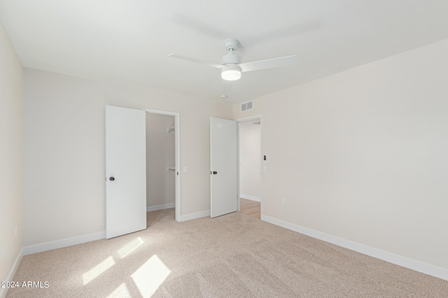 unfurnished bedroom featuring a closet, light colored carpet, and ceiling fan