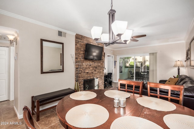 tiled dining area with ceiling fan with notable chandelier, crown molding, and a fireplace