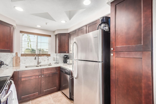 kitchen with decorative backsplash, appliances with stainless steel finishes, light stone counters, and sink