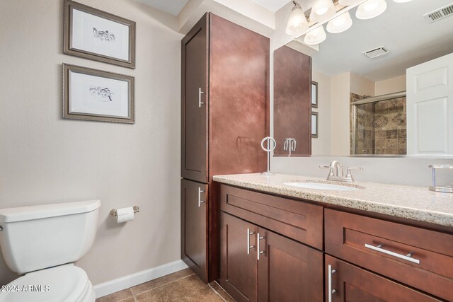 bathroom featuring toilet, vanity, tile patterned floors, and a shower with door