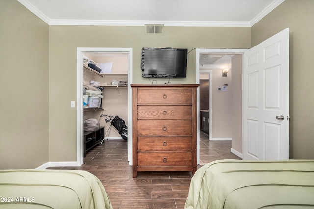 bedroom with crown molding, a closet, dark hardwood / wood-style flooring, and a spacious closet