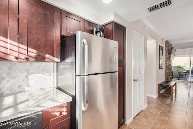 kitchen featuring decorative backsplash, light stone counters, ornamental molding, stainless steel refrigerator, and light tile patterned flooring