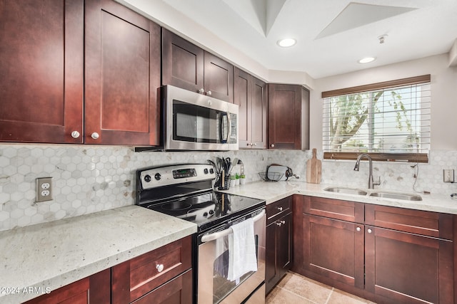 kitchen with light stone countertops, decorative backsplash, stainless steel appliances, sink, and light tile patterned floors