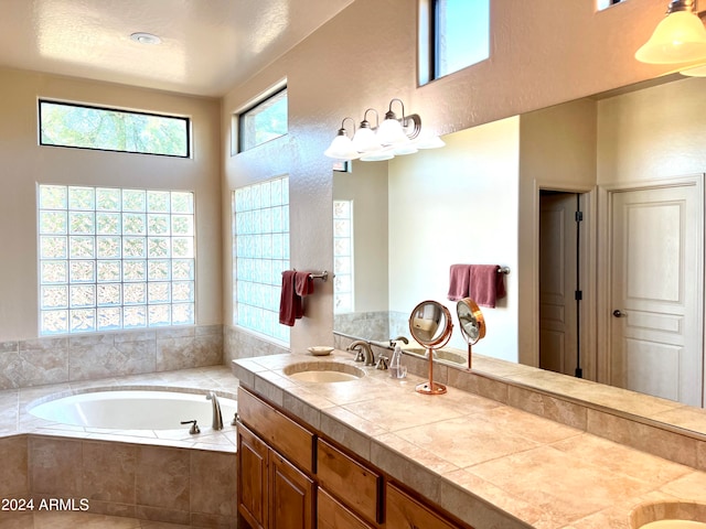 bathroom featuring tiled tub, vanity, and a textured ceiling