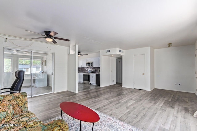 living room with ceiling fan, visible vents, and wood finished floors