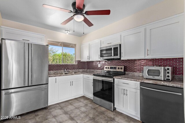 kitchen featuring stainless steel appliances, white cabinetry, and backsplash