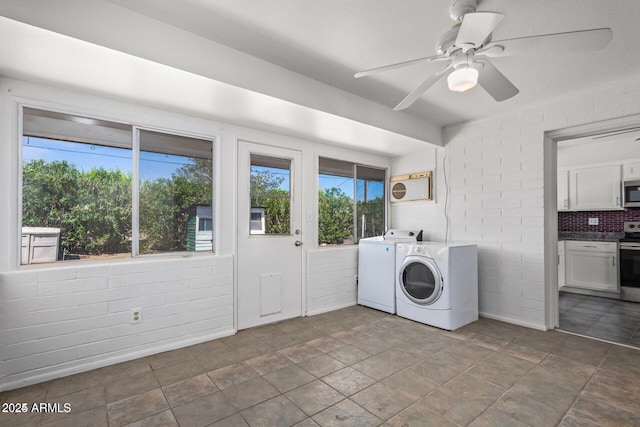 clothes washing area with ceiling fan, brick wall, separate washer and dryer, and laundry area