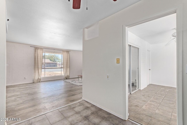 empty room with light wood-style floors, ceiling fan, and baseboards