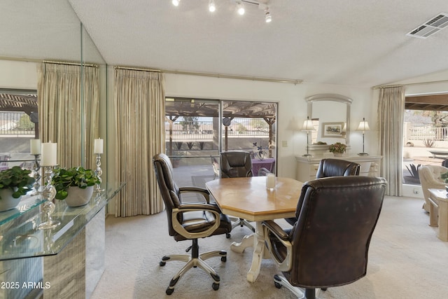 dining space with a wealth of natural light, lofted ceiling, and light colored carpet