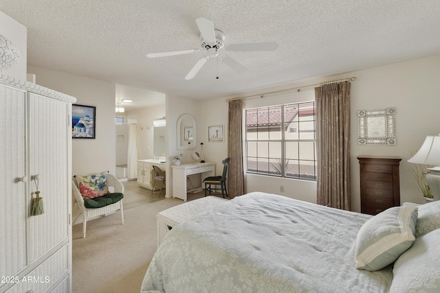 carpeted bedroom with ceiling fan, a textured ceiling, and ensuite bath