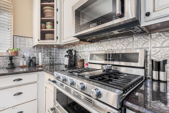 kitchen featuring tasteful backsplash, white cabinetry, dark stone counters, and stainless steel appliances