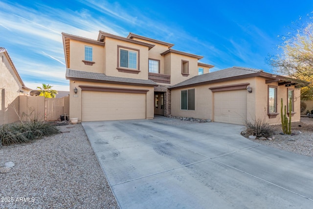 view of front of house featuring driveway, a tile roof, fence, and stucco siding