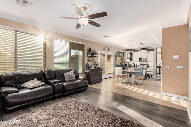 living room with ceiling fan, ornamental molding, and light tile patterned floors