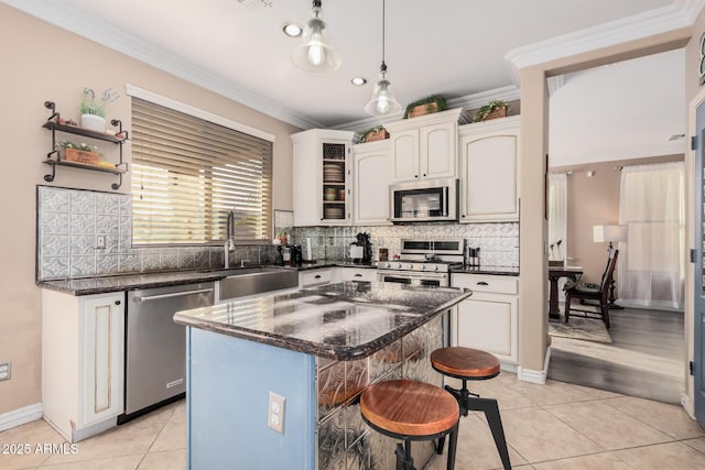 kitchen featuring appliances with stainless steel finishes, sink, white cabinetry, light tile patterned floors, and a kitchen island