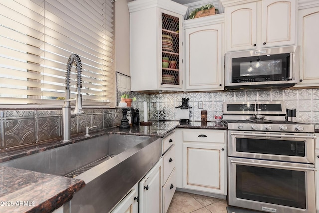 kitchen with white cabinets, stainless steel appliances, light tile patterned floors, and sink