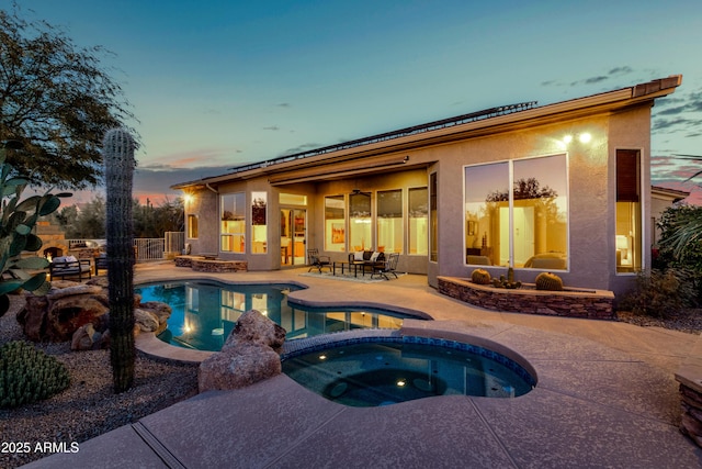 pool at dusk featuring a patio area and an in ground hot tub