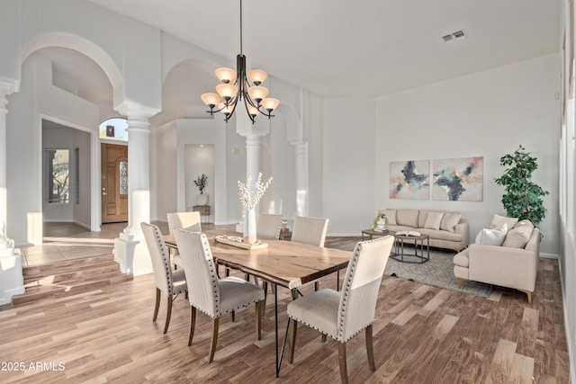 dining room with ornate columns, an inviting chandelier, and hardwood / wood-style floors