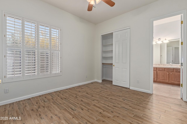 unfurnished bedroom featuring sink, ensuite bathroom, ceiling fan, light hardwood / wood-style floors, and a closet