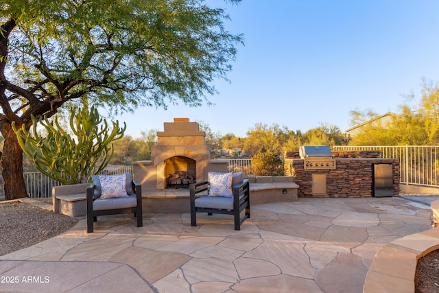 view of patio / terrace with exterior kitchen, an outdoor stone fireplace, and area for grilling