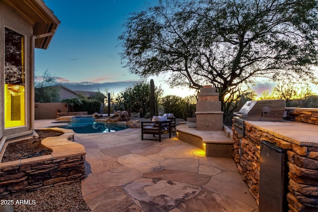 patio terrace at dusk with a fenced in pool and area for grilling