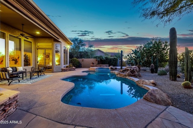 pool at dusk featuring ceiling fan and a patio area