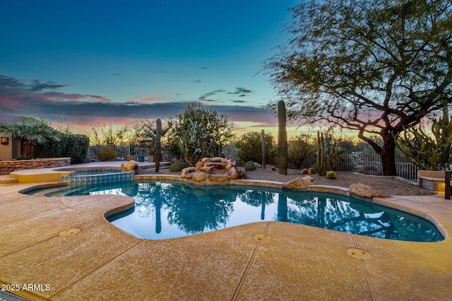 pool at dusk with a patio area and an in ground hot tub