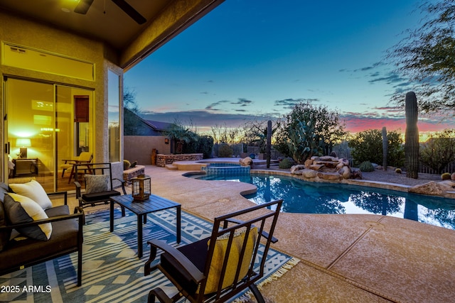 pool at dusk featuring an outdoor hangout area, a patio area, ceiling fan, and an in ground hot tub