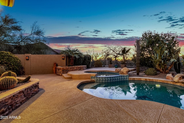 pool at dusk featuring a patio area and an in ground hot tub