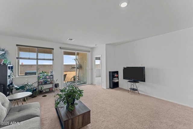 living area with light carpet, visible vents, and baseboards