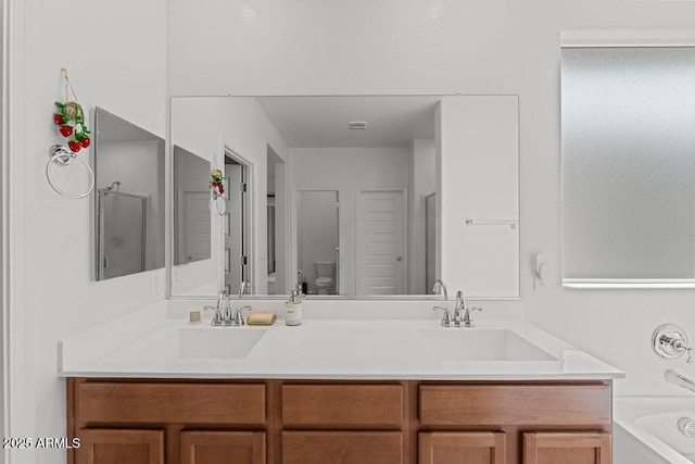 bathroom with a washtub, double vanity, a sink, and toilet