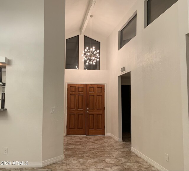 tiled foyer entrance with high vaulted ceiling, beamed ceiling, and a notable chandelier