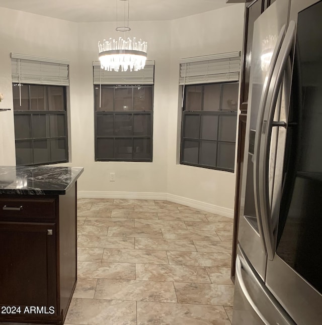 kitchen featuring dark stone countertops, pendant lighting, dark brown cabinetry, and stainless steel fridge with ice dispenser